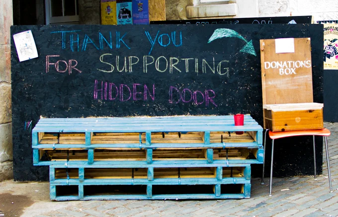 Sign saying Thank You For Supporting Hidden Door, next to a donations box.