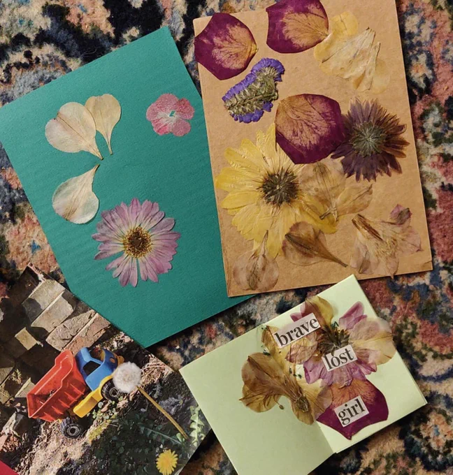 Floral collàges scattered around. One piece of paper has the text 'brave lost girl' on it taken from s newspaper and next to it is a photo of a toy truck