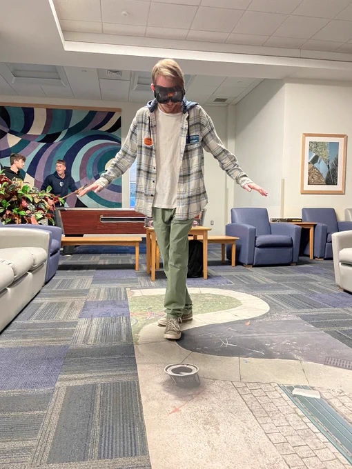 Brandon, a Penn College of Technology student tries to keep his balance while wearing impairment goggles during a safety event.
