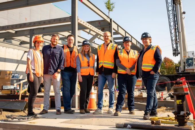 Seven team members stand in front of construction site.