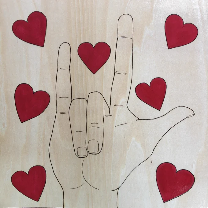 A hand is pictured showing the ASL sign for “I love you.” Red hearts surround the hand.
