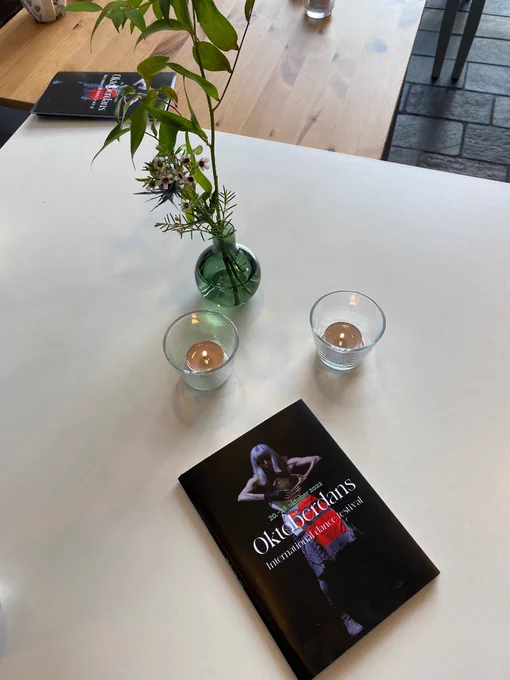 Oktoberdans brochure on table next to candles and plant