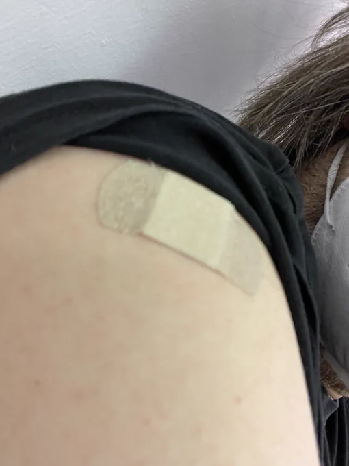 Entblößte Schulter mit Impfpflaster. 