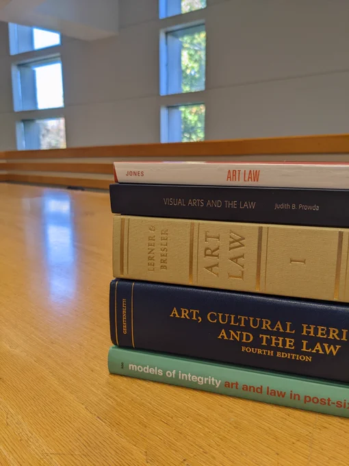 Five books related to art law stacked on a table at the University of Iowa Law Library.