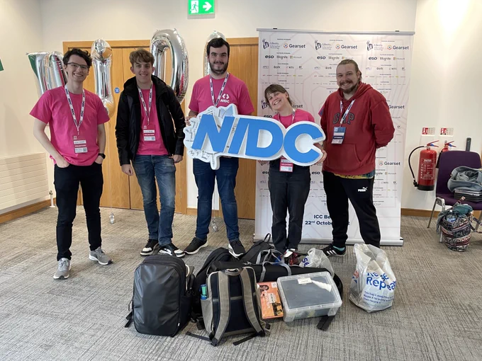 The Northern Ireland Raspberry Jam Team at NIDC with their equipment from their workshop holding a NIDC sign.