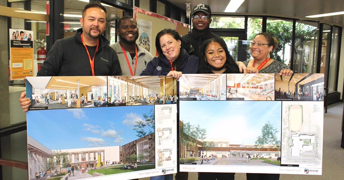 Six people holding two school design boards.