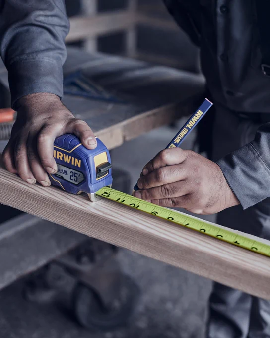 Man makes measurements on a 2x4 using a Strait-line® Tape Measure.