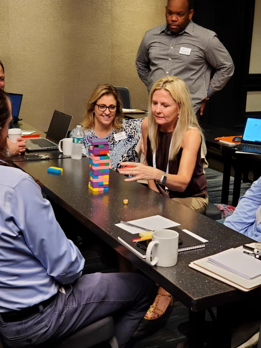 Woman playing a tower stacking game while others watch. 