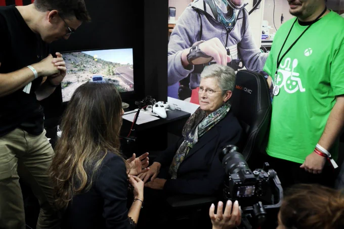 La ministre Geneviève DARRIEUSSECQ est assise devant une console de jeu et découvre les consoles adaptées qui permettent aux personnes handicapées de jouer.