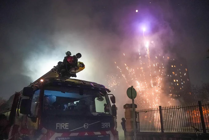 Fire engine with firework going off in background.