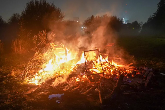 Small lit bonfire on patch of grass.