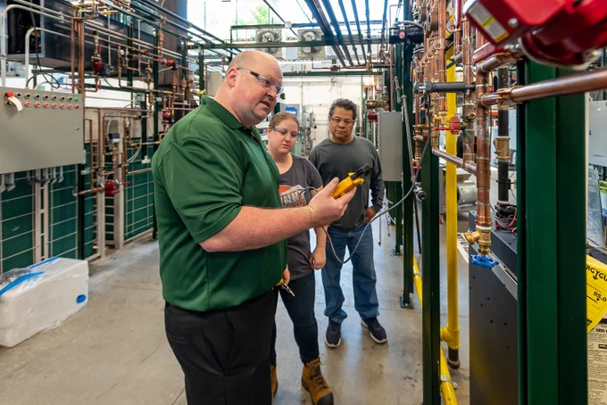 An instructor showing his students some pipes, an image featured in the ATE Impacts Book.
