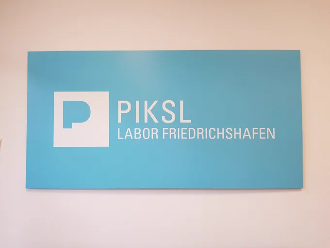 Ein großes PIKSL Labor Friedrichshafen Schild hängt an der Wand.
