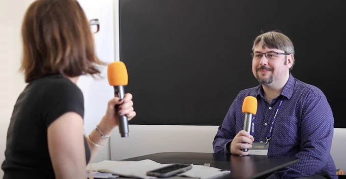 Two people talking to one another into microphones.