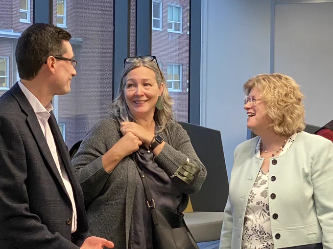 Three people chat happily at the opening event.