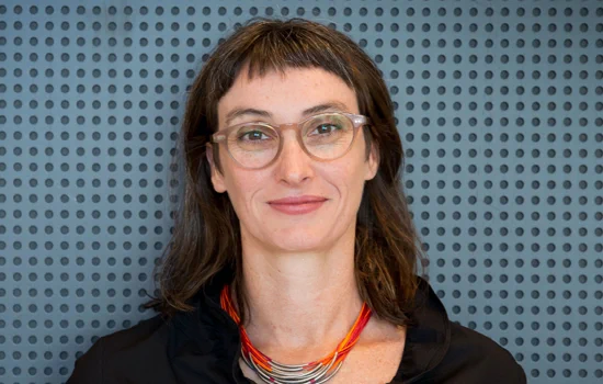 Image of Prof Catherine Mills smiling at the camera, with a blue and grey polka dot background