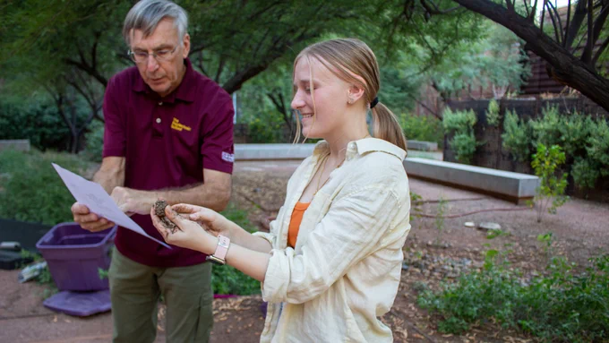 Female student talking to Senior Lecturer Al Brown about adding water to soil to determine its composition.