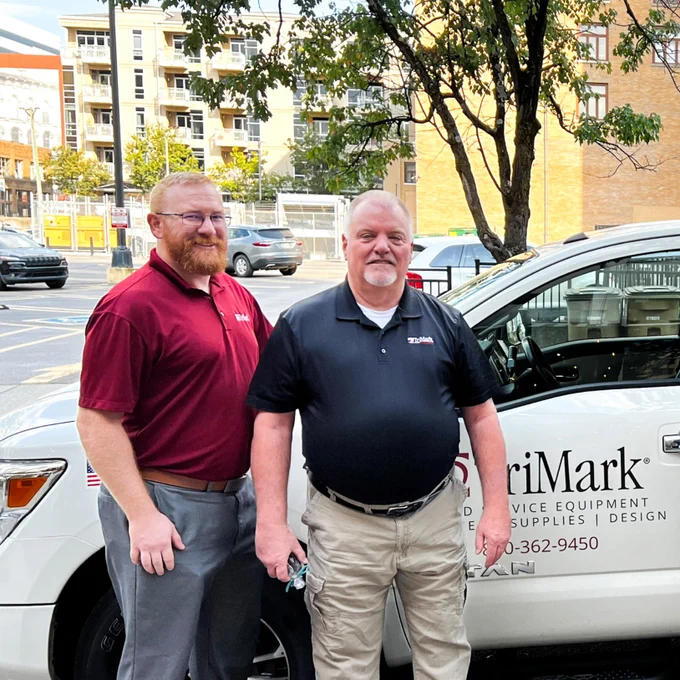 Two individuals next to a TriMark pick-up truck