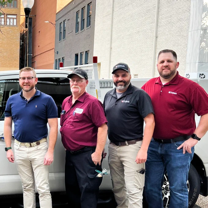 Four individuals next to a vehicle