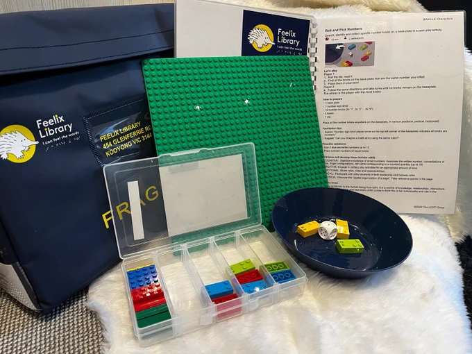 Lego braille bricks in a plastic box, in front of a Feelix kit.