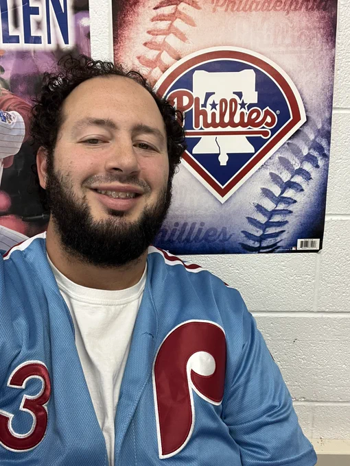 Mr. Shore in his Phillies jersey in front of a Phillies poster.