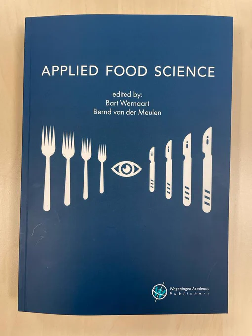 Blue cover of the paperback Applied Food Science, showing the title and editors (Bart Wernaart & Bernd van der Meulen) with a visual of forks and knives watched by one eye in the middle of these forks & knives. 