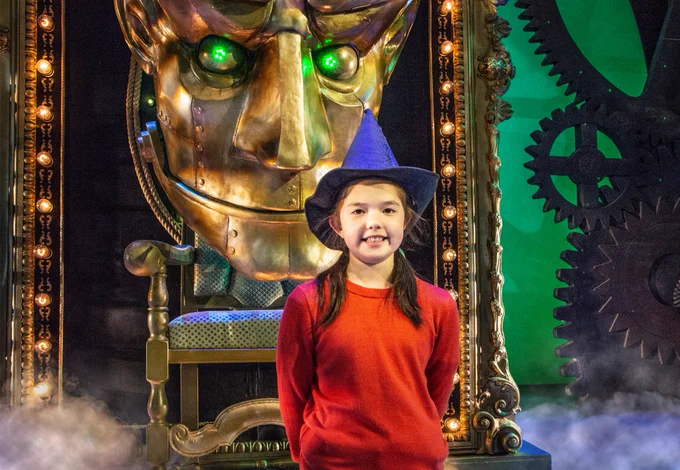 Prize winner on the stage of Wicked wearing a witch hat.