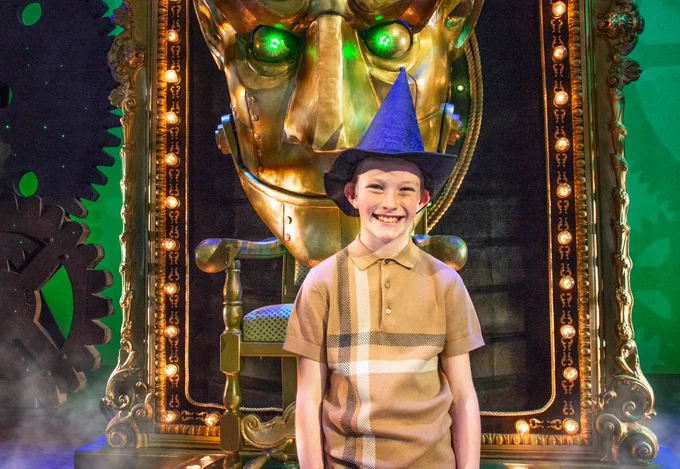 Prize winner on the stage of Wicked wearing a witch hat.