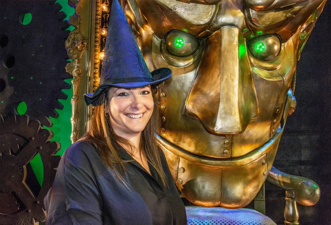 Prize winner on the stage of Wicked wearing a witch hat.