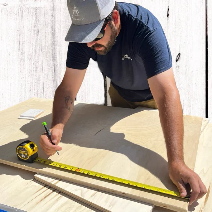 A builder using the STANLEY® FATMAX® Classic Tape Measure to make measurements on a wooden panel. 