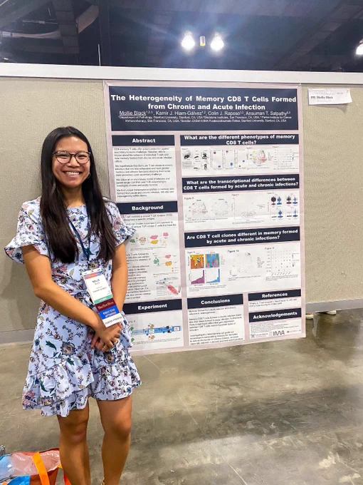 Girl in blue floral print dress stands next to a scientific poster that’s titled “The Heterogeneity of Memory CD8 T Cells Formed From Chronic and Acute Infection”