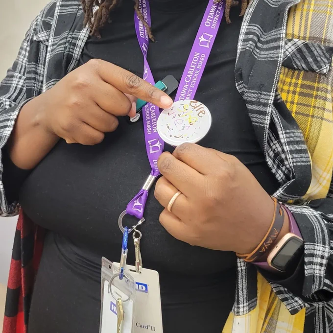 Me wearing a pin with student printing of pronouns elle she her 