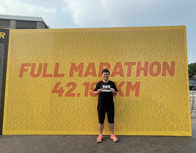 Hung Nguyen holds the bib, stands in front of the background with names of all Full Marathon participants in Long Bien Marathon, Vietnam.
He looks happy 😊 but a little bit nervous 😢