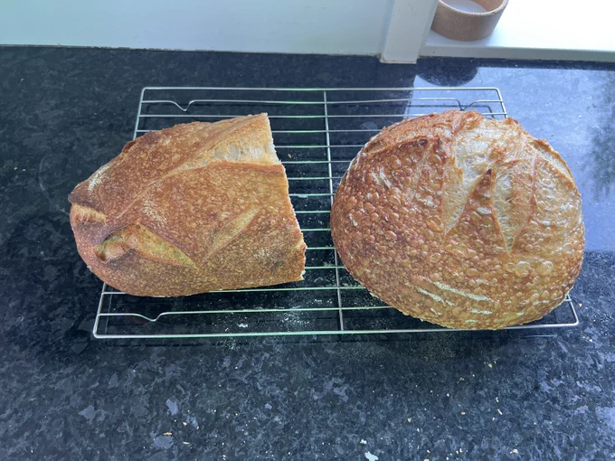 Sourdough bread on a cooling rack. One whole loaf and the other half eaten