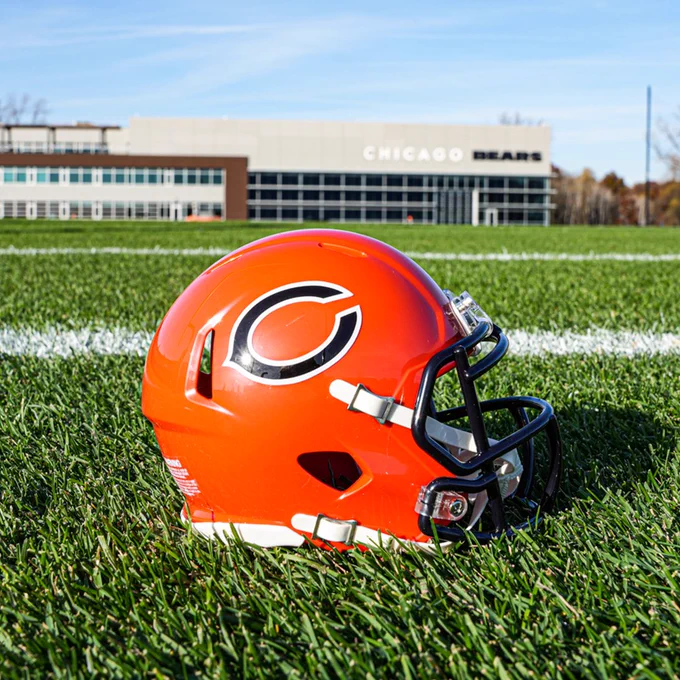 Orange mini helmet sitting on grass at Halas Hall