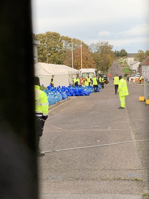 Sexurity at Manston camp and pikes of blue bags containing belongings