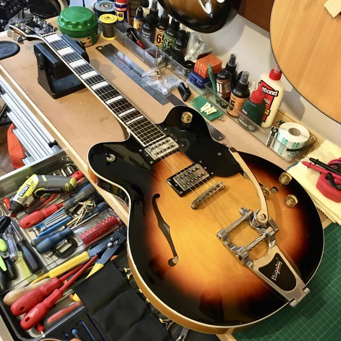 A hollowbody Gretsch guitar with a Bigsby tremolo and Pearloid inlays on a work bench at Guitar Bath, England