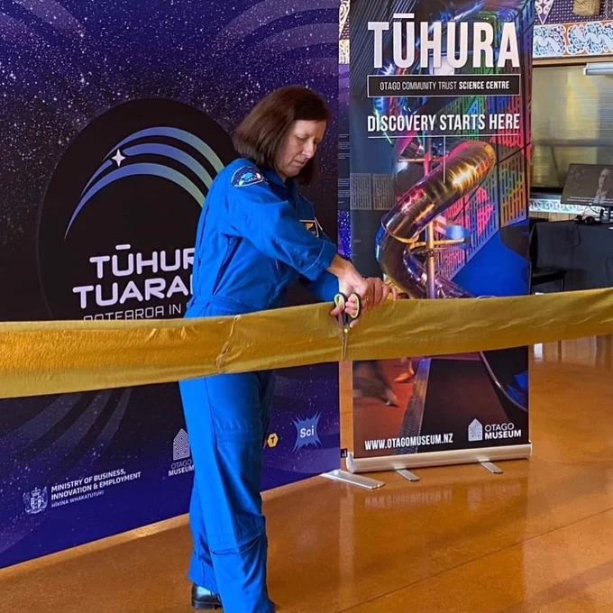 NASA astronaut Shannon Walker uses scissors to cut a gold banner, symbolising the official opening of the Tūhura Tuarangi – Aotearoa in Space exhibition in Bluff.