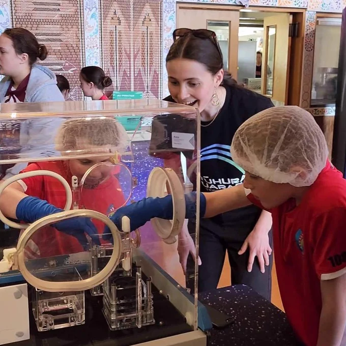 Children wearing hairnets and gloves get hands-on with displays that will tour the country as part of the Tūhura Tuarangi – Aotearoa in Space roadshow.