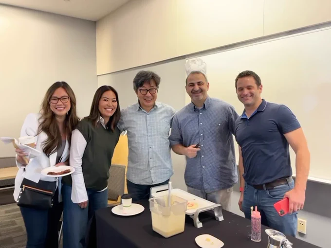 A picture of five people smiling at a Microsoft Giving Campaign breakfast event. They are standing in front of a stove with bowl of pancake batter.