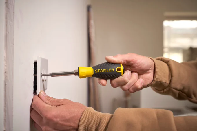 A pro using a STANLEY® Quick Change 6-Way Screwdriver to screw in an outlet cover.