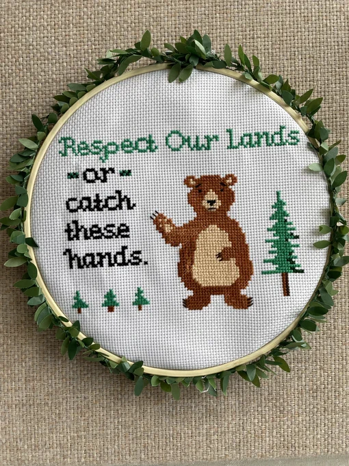 A cross stitch depicting a chubby brown bear standing next to four firs. The words “Respect our lands or catch these hands” frame the bear. The bear bears an expression of concern. Or maybe it’s hunger? Hunger FOR RESPECT. Seriously, don’t feed the bears — or any wildlife for that matter. Judy is counting on you. Don’t disappoint Judy.