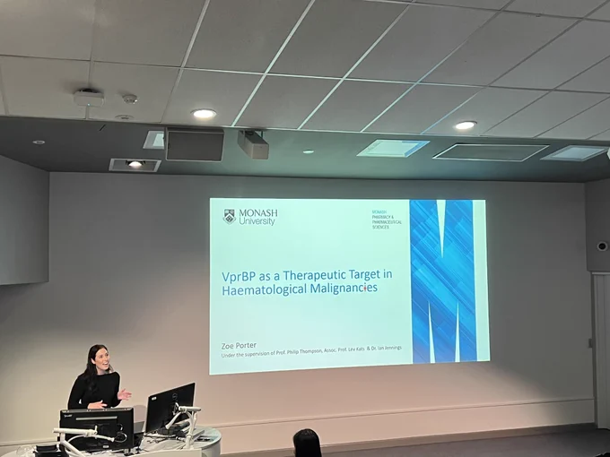 Zoe standing behind a lectern talking about a new haematological malignancy therapeutic target