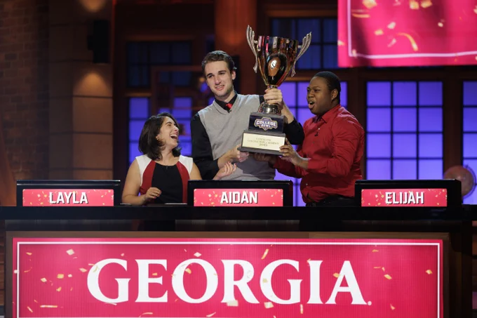 Layla, Aiden and Elijah celebrate and hold the College Bowl trophy in the air on the set of the finale episode. 
