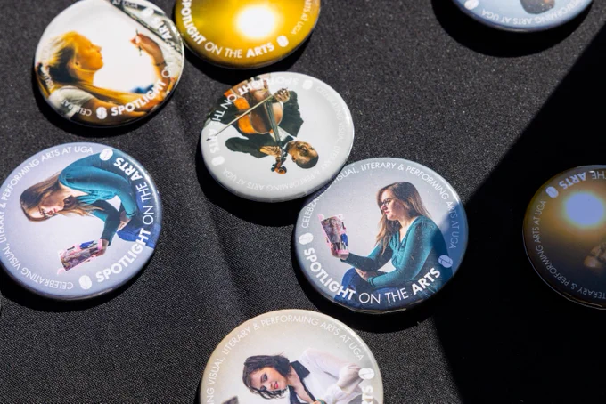 Spotlight on the Arts promotional pins displayed on a table. 
