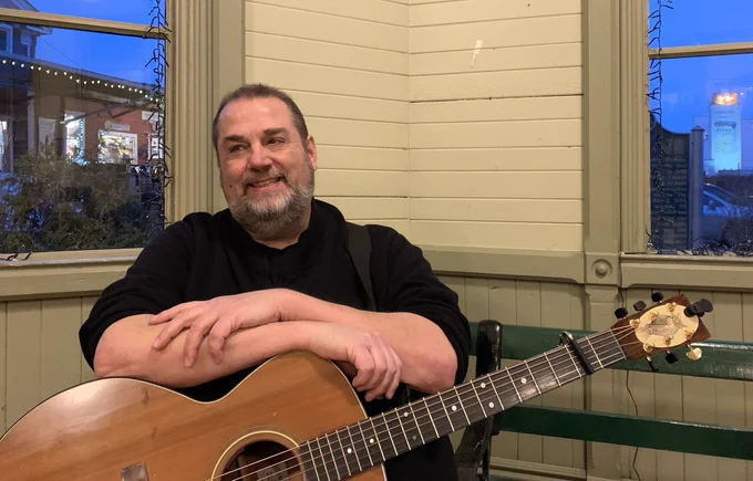 [Matt Watroba smiles with his guitar.]