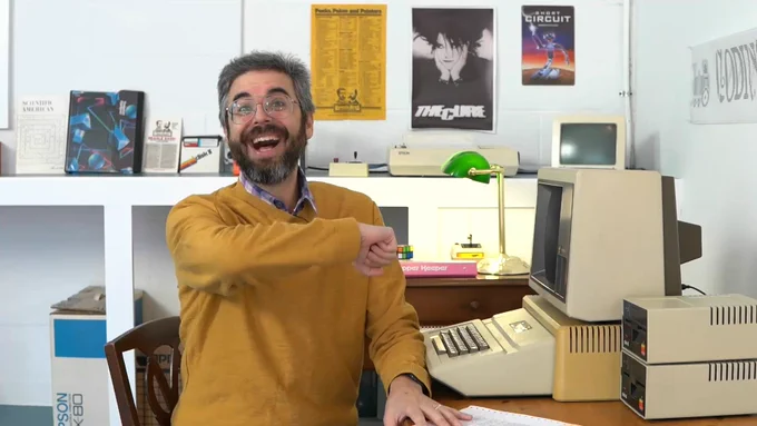 Close up of a man siting smiling by a desk with an Apple II computer.