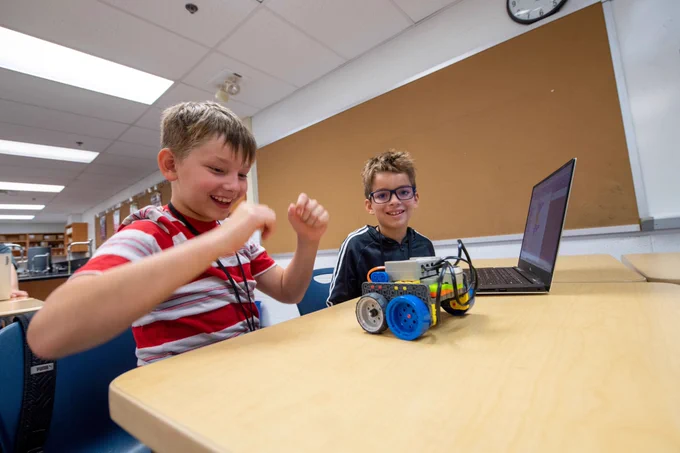 Two elementary children are coding a robot. 