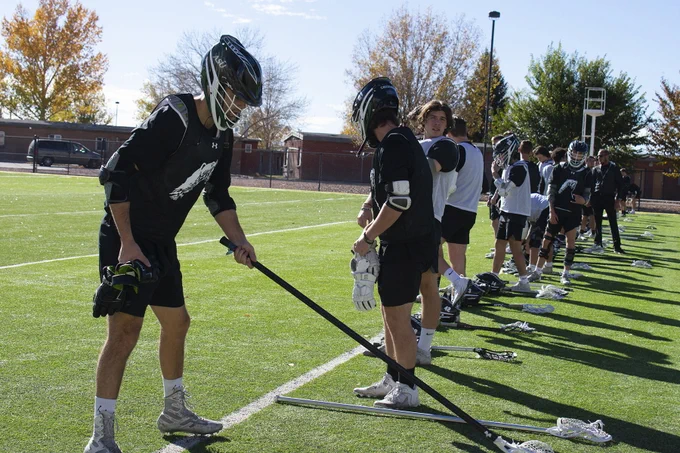 Lacrosse players line up with their equipment. 