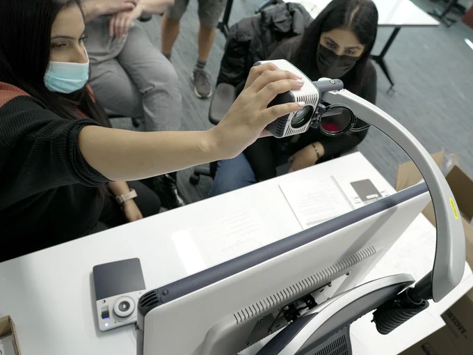A woman adjusting the camera orientation of the Davinci desktop magnifier, by @EnhancedVision